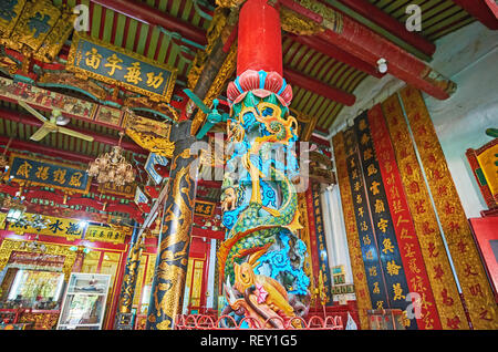 YANGON, MYANMAR - 17. FEBRUAR 2018: Die landschaftlich schöne geschnitzte Spalte mit den östlichen Drachen, in hellen Farben gestrichen, in Langen Shan Tang Clan Tempel, in entfernt Stockfoto