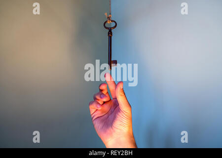 Menschen Hand erreichen für Vintage Schlüssel hängen an einen String. Geschäftlicher Erfolg Freiheit Konzept Konzept für Bestrebungen, Leistung und Incentive Stockfoto
