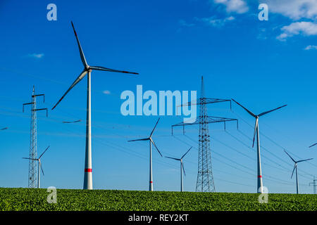 Einige Windkraftanlagen sowie die Powerline in der landwirtschaftlichen Landschaft Stockfoto