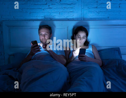 Junges Paar spät abends im Bett aus Smartphones besessen, Spiele, Social Media und Apps Jeder andere ignorieren in Beziehung Kommunikation prob Stockfoto