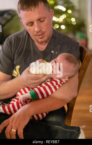 Denver, Colorado - Adam Hjermstad Sr. Feeds seiner vier Monate alten Sohn, Hendrix. Stockfoto