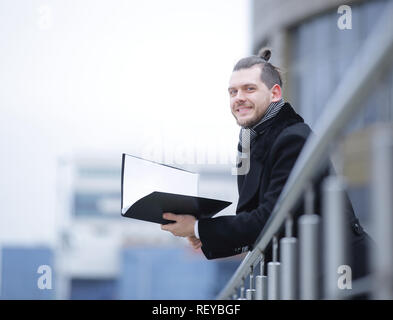 Lächelnd business Mann in warme Kleidung mit Papieren Stockfoto
