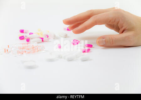 Die Abhängigkeit von Medikamenten und Drogen in modernen Zeiten: Nahaufnahme der Hand einer jungen Frau über die verschiedenen Tabletten und Ampullen auf Tisch und weiß bac Greifer Stockfoto