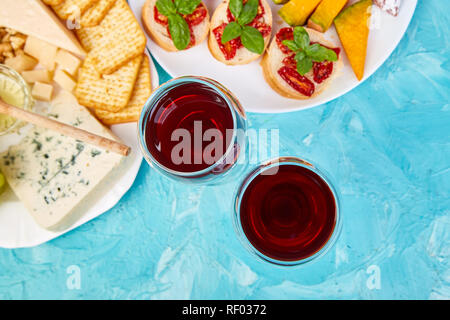 Italienische Antipasti Wein Snacks. Antipasto catering Plattenteller mit ruckartiger, Salami, Käse, Trauben, Oliven, Gurken, Melonen, Brushettas auf Blau backgrou Stockfoto