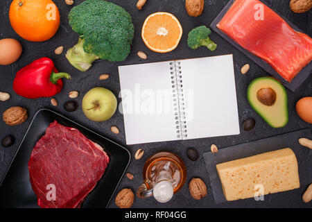 Bild von Lebensmitteln für Ernährung, sauberes Notepad auf schwarzen Steintisch im Studio. Stockfoto