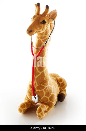 Kleines Spielzeug giraffe Hören auf seinen Herzschlag mit einem bunte Rote Grütze, wie es kniet auf weißem Hintergrund in ein Konzept der pädiatrischen healthcar Stockfoto