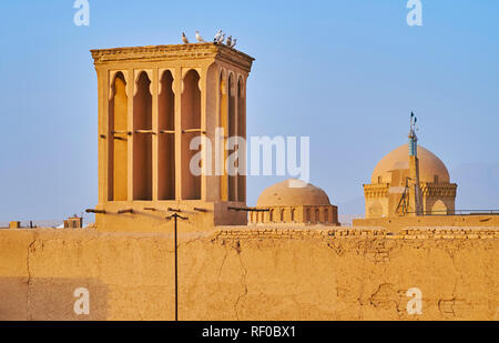 Die kleine Herde der weißen Tauben sitzt auf dem mittelalterlichen Adobe badgir (windcatcher) mit Blick auf die Kuppel von Alexanders Gefängnis auf dem Hintergrund, Stockfoto