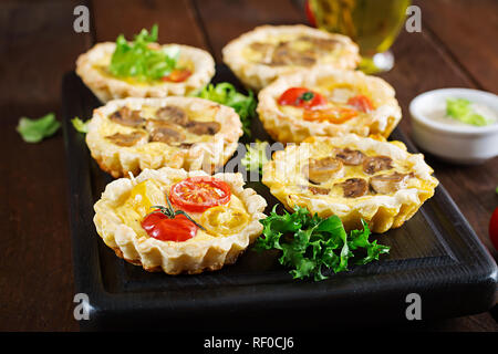 Pilze, Cheddar, Tomaten Törtchen auf Holz- Hintergrund. Mini Torten. Leckere Vorspeisen, Tapas, Snacks. Stockfoto