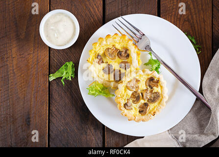 Pilze, cheddar Törtchen auf Holz- Hintergrund. Mini Torten. Leckere Vorspeisen, Tapas, Snacks. Ansicht von oben. Flach Stockfoto