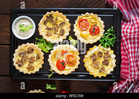 Pilze, Cheddar, Tomaten Törtchen auf Holz- Hintergrund. Mini Torten. Leckere Vorspeisen, Tapas, Snacks. Ansicht von oben. Flach Stockfoto