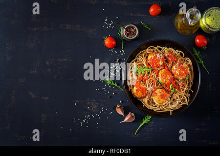 Italienischen Pasta. Spaghetti mit Fleischbällchen und Parmesan in schwarze Platte auf dunklen rustikalen, mit Holz Hintergrund. Abendessen. Ansicht von oben. Slow food Konzept Stockfoto