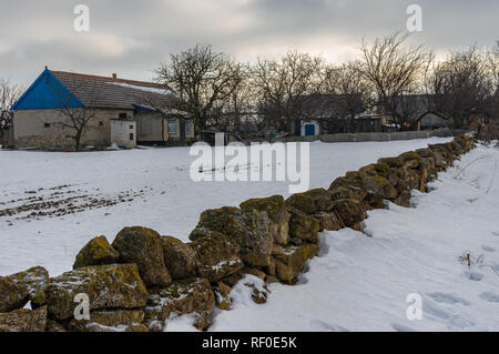 Winterlandschaft mit bäuerlichen Gehöft mit kleinen Steinmauer in Skelky Dorf, Oblast Saporischschja, Ukraine umgeben Stockfoto