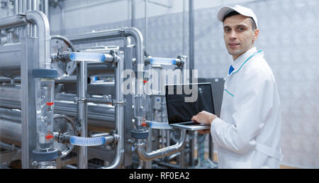 Techniker mit einem Laptop in der Hand an der Milchfabrik Stockfoto