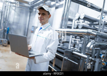 Techniker mit einem Laptop in der Hand an der Milchfabrik Stockfoto