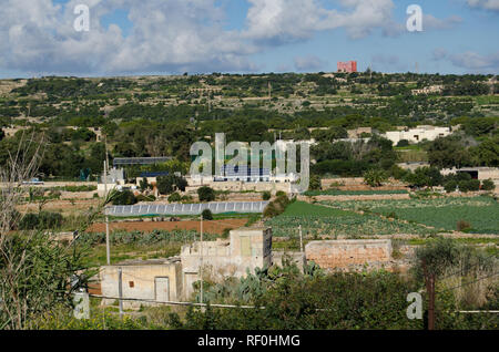 Mellieha, Malta - 30 Dezember 2018 - Sonnenkollektoren auf dem Haus in der Mitte der Landwirtschaft Felder unter Roter Turm - Energiekonzept Stockfoto