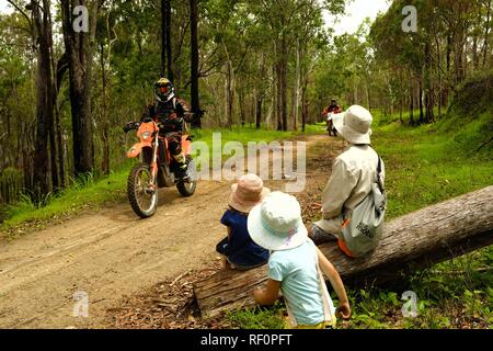 Dirt Bikes reiten auf einem Feuer auf der Straße draußen im Wald, Mia Mia State Forest, Queensland, Australien Stockfoto