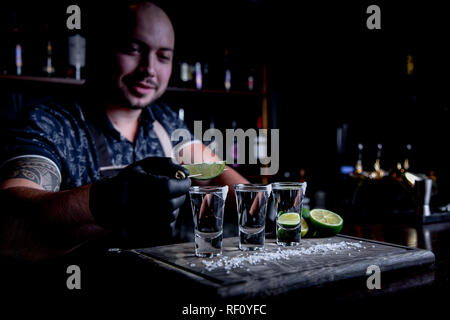 Aperitif mit Freunden in der Bar, drei Gläser Alkohol mit Kalk und Salz für die Dekoration. Tequila shots, selektiver Fokus Stockfoto
