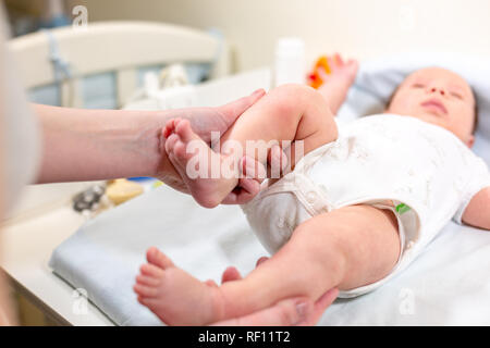 Mom macht Übung lächelndes Kind. baby Neugeborenen genießt Massage von der Mutter Stockfoto