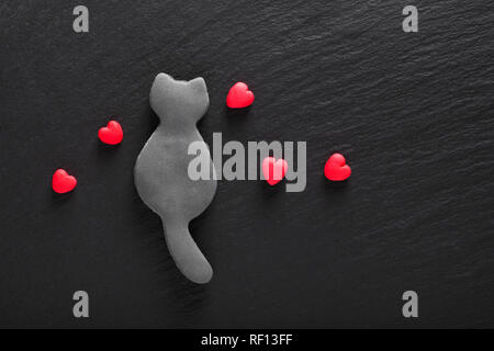Valentine Hintergrund edibale genießbare Single black cat Cookies und Fondantzucker roten Herzen auf schwarzen Hintergrund mit Kopie Raum Stockfoto