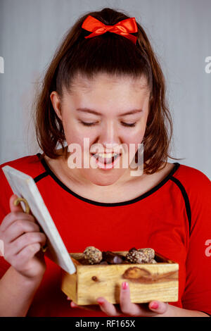 Junge fröhliches Mädchen in Holding öffnen mit Schokolade Süßigkeiten Feier des neuen Jahres und Weihnachten Stockfoto