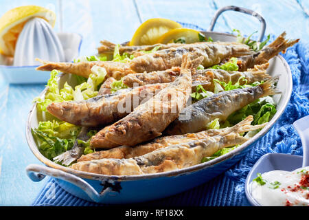 Crispy batter fried Griechische Sardinen, Sardinen oder Sardellen in einem alten Jahrgang ovale Schale gekleidet mit Zitrone und serviert mit raita in der Nähe zu sehen. Stockfoto