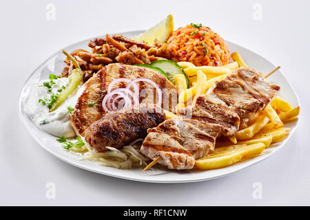 Mixed Grill griechische Platte mit Souvlaki, souzuki Steak und würzigem Schweinefleisch Spieße mit Tomate Reis Pilav, Kartoffel, Pommes und Salat serviert. Stockfoto