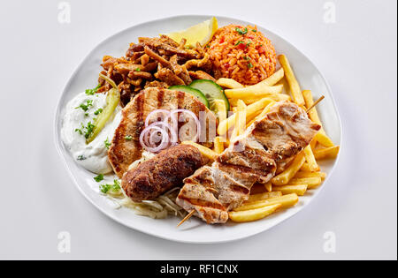 Regionalen griechischen Grillteller mit gebratenen Kartoffelchips und Tomaten Pilav mit Souvlaki, souzuki Steak und Schwein am Spieß serviert mit raita Stockfoto