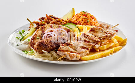 Traditionelle griechische Mixed Grill Platte mit gegrilltem Schweinefleisch Spieße, slouvaki ans souzuki Steak serviert mit Pommes frites, Tomate, Reis Pilav und raiti Stockfoto