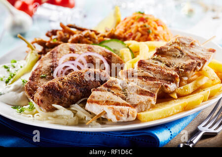 Griechische Grill platter mit Gyros, Souvlaki und würzigem Schweinefleisch Spieße mit Kartoffelchips und Tomate Reis Pilav in der Nähe zu sehen, serviert Gemischt Stockfoto