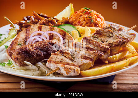 Griechische Grill platter mit Souvlaki, souzuki Steaks und gegrilltem Schweinefleisch Spießen serviert mit erfrischenden raiti Joghurt Dressing und Pilav Stockfoto