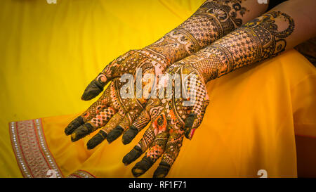 Henna mehendi Malerei, auf die Braut Hände mit dem gelben Kleid Hintergrund. Hochzeit Vorbereitung in Indien. Stockfoto