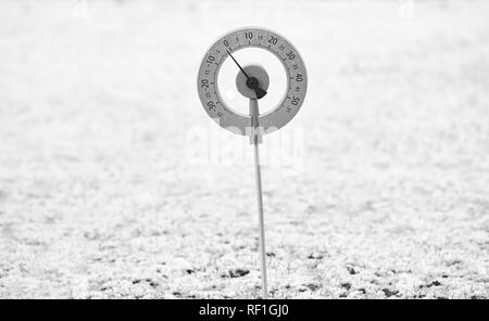 Garten Thermometer auf einem schneebedeckten Rasen zeigt eine Temperatur knapp unter null Grad Celsius. Stockfoto