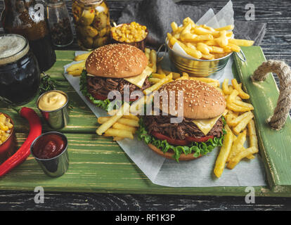 Burger zog Rindfleisch grillen, Sandwich, Pommes Frites, Sauce, dunkles Bier, Korn, auf einer hölzernen Fach Stockfoto