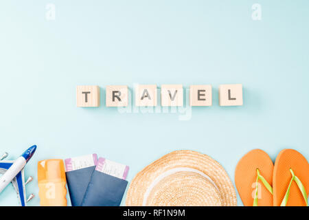 Blick von oben auf die holzwürfel mit travel Schriftzug, Strohhut, Flip Flops, Pässe und Flugtickets auf blauem Hintergrund Stockfoto