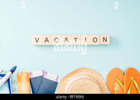 Blick von oben auf die holzwürfel mit travel Schriftzug, Strohhut, Flip Flops, Pässe und Flugtickets auf blauem Hintergrund Stockfoto