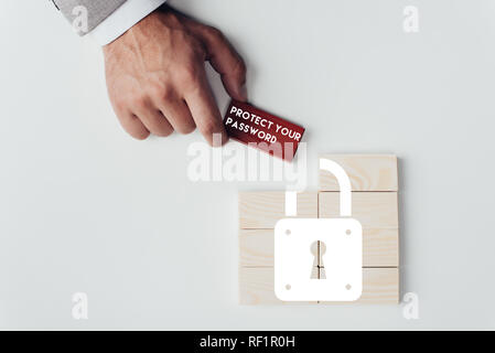 Teilansicht der Mann mit Ziegel mit "Schützen Sie Ihr Passwort' Schriftzug über Holzblöcke mit Schlosssymbol isoliert auf weißem Stockfoto