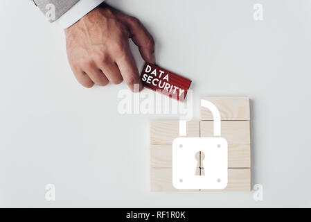 Teilansicht der Mann mit Ziegel mit Sicherheit 'data'-Schriftzug über Holzblöcke mit Schlosssymbol isoliert auf weißem Stockfoto