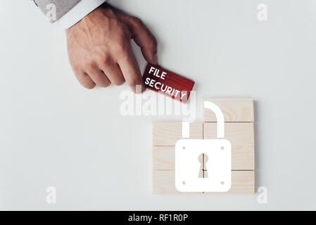 Teilansicht der Mann mit Ziegel mit 'File Security'-Schriftzug über Holzblöcke mit Schlosssymbol isoliert auf weißem Stockfoto