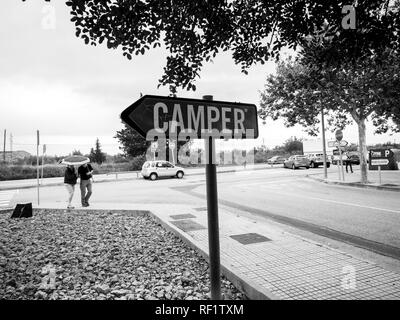 INCA, PALMA DE MALLORCA, SPANIEN - 8. Mai 2018: Paar für Camper Schuhfabrik Hauptsitz in Inca mit Schriftzug auf totem Pfeil Verkehrsschild - Schwarz und Weiß Stockfoto