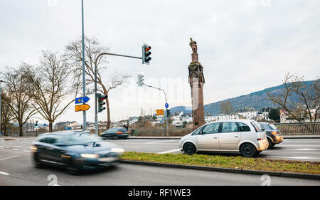 TRIER, Deutschland - Dec 21, 2015: Zeile der Autos und der Statue des Kaisers Konstantin eine Krone mit einem Kreuz, auf eine Spalte am Fuße des Kaiserstraße Imperial Straße auf der Mosel Stockfoto