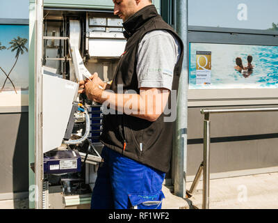 KARLSRUHE, Deutschland - 11. MAI 2018: Seitenansicht der männlichen Service Operator Reparatur der Fahrkarte Fahrkarte service Automaten in der Nähe des Eingangs des Karlsruhe Flughafen entfernt Stockfoto