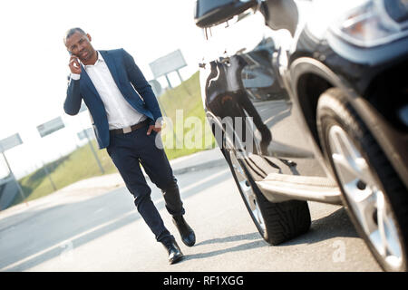Junge Menschen auf dem Weg zum Auto sprechen auf dem Smartphone ernst Stockfoto