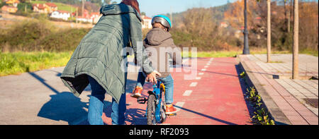 Mutter lehre Sohn ein Fahrrad in cycleway zu fahren Stockfoto