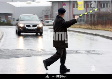 Alter Mann, der versucht, eine Straße mit seinem Spazierstock mit einem entgegenkommenden Auto, Mettmann, Nordrhein-Westfalen auf Langsam zu Kreuz Stockfoto