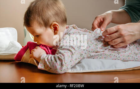 Hände von Mutter Dressing ihr Baby liegend Stockfoto