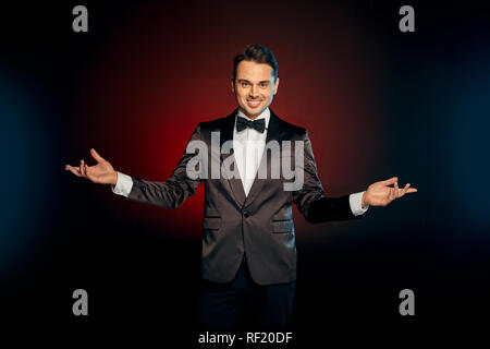Berufliche Tätigkeit. Showman in der Klage stehen isoliert auf Wand Hände beiseite lächelnd verspielt Stockfoto