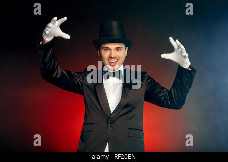 Berufliche Tätigkeit. Showman, Handschuhe und Hut stehen isoliert auf Wand zu zeigen, Lächeln aufgeregt Stockfoto