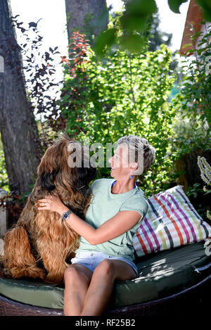 Lächelnde Frau mit ihrem Hund in den Garten Stockfoto