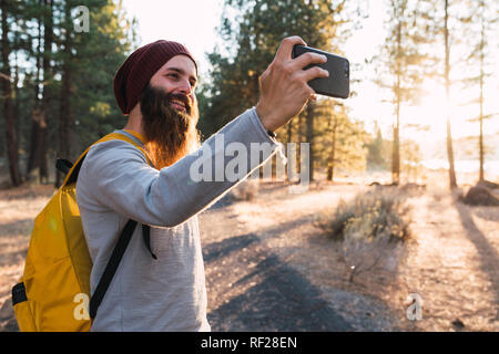 USA, Kalifornien, lächelnd bärtiger Mann mit einem selfie in einem Wald in der Nähe des Lassen Volcanic National Park Stockfoto