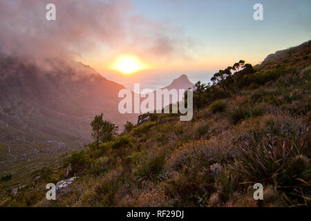Ein Sonnenuntergang Wanderung auf den Devil's Peak unglaubliche Aussicht afords wie die Sonne taucht unter dem Atlantischen Ozean Horizont, Cape Town, Western Cape Provinz, Südafrika Stockfoto